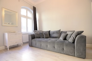 Relax in this stylish living room with a sofa, dresser, and large window.