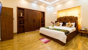 Quarto com cama grande, guarda-roupa de madeira e luminária no teto.