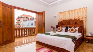 Um quarto espaçoso com uma cama grande, cabeceira de madeira e uma varanda com vista para prédios.