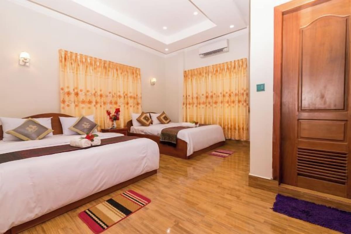 Ein Hotelzimmer mit zwei Betten, Holzboden und einer großen Holztür.