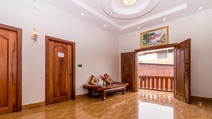 Um corredor amplo com pisos de madeira lustrada, portas de madeira e um banco com almofadas.