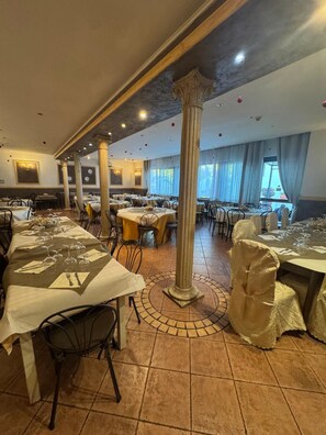 A restaurant with multiple tables, chairs, and a central column. - Park Hotel Serenissima (Sacrofano)