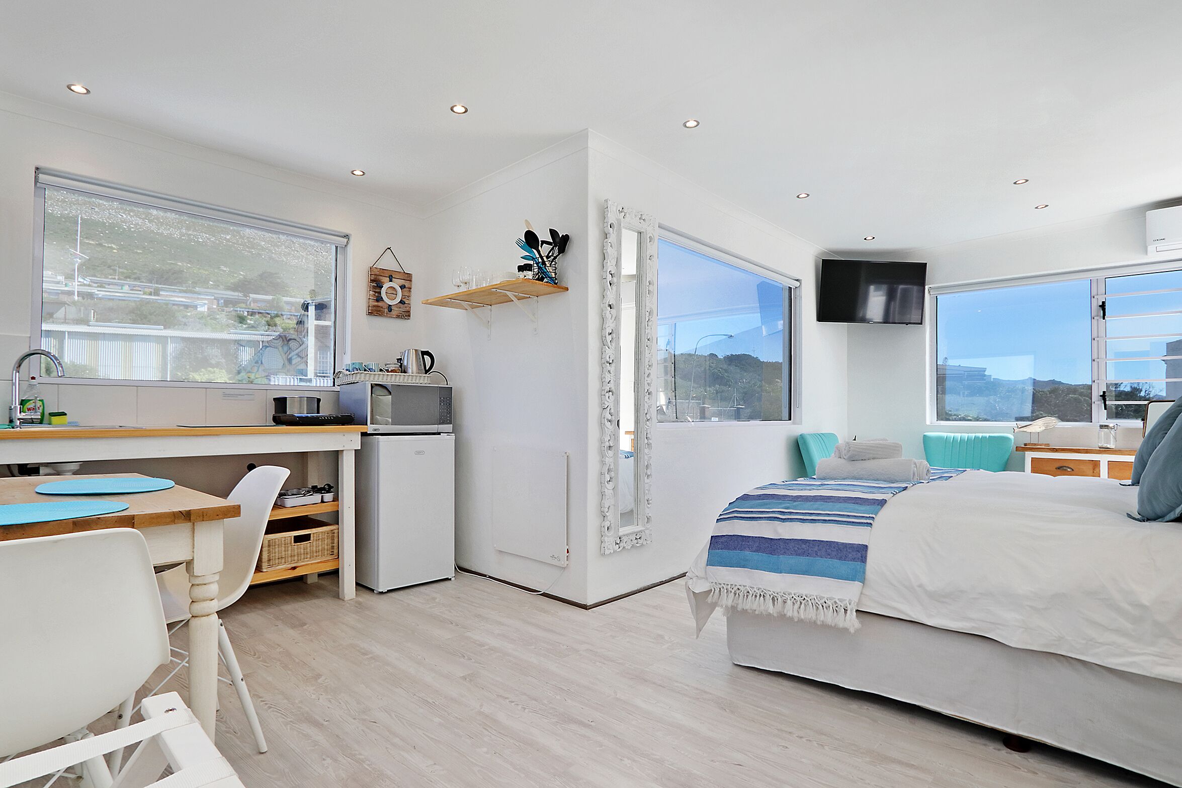 A modern, well-lit room with a bed, a desk, and a television.