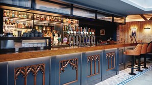 Eine Bar mit einer langen Theke, mehreren Zapfhähnen und einer Auswahl an Flaschen. Bietet Sitzgelegenheiten an der Bar und verfügt über eine dekorative Decke.