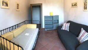 A room with a bed, a sofa, a dresser, and a door. - Frantoio-Large and Beautiful family apartment -Agriturismo San Jacopo (Reggello)
