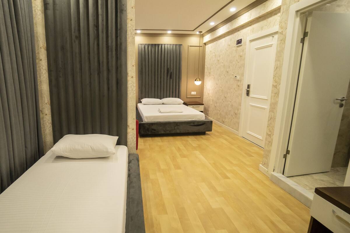 A hotel room with a single bed, a bedside table, a wardrobe, and a mirror.