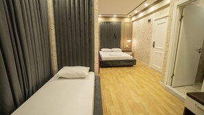 Une chambre d’hôtel avec un lit simple, une table de chevet, une armoire et un miroir.