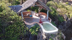 Un espace piscine extérieur isolé, doté d’une structure en bois rustique et entouré d’une végétation luxuriante.