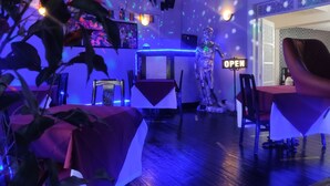A restaurant interior with a bar area, a neon 'OPEN' sign, and a skeleton decoration. - Mardi Gras Hotel (Blackpool)