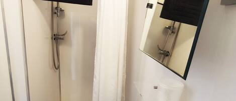 Un baño con una bañera blanca, una ducha con puerta de vidrio, un lavabo blanco y un espejo sobre el lavabo.