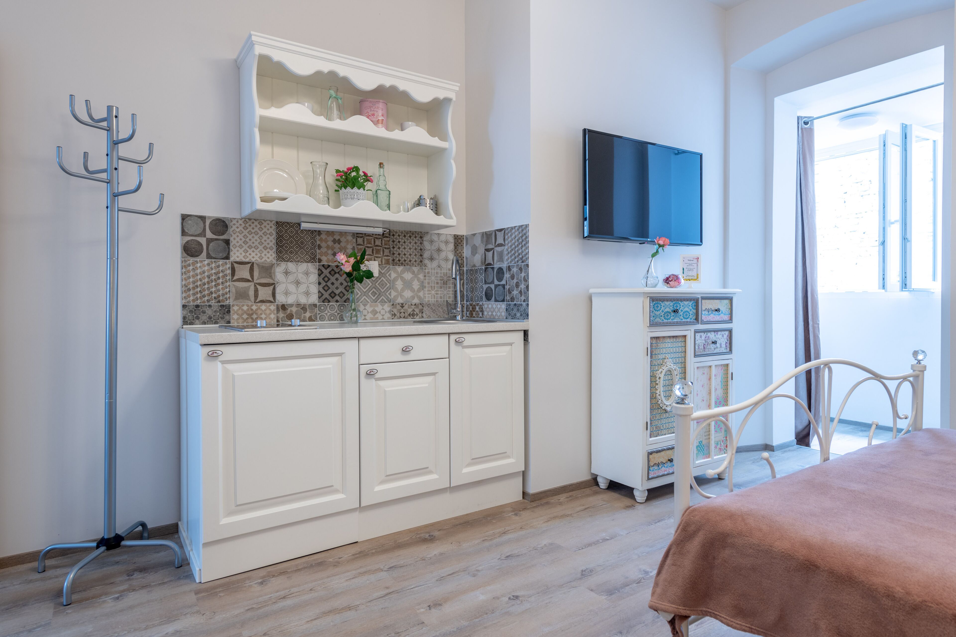 Una cocina moderna con armarios blancos, salpicadero de azulejos y suelo de madera.