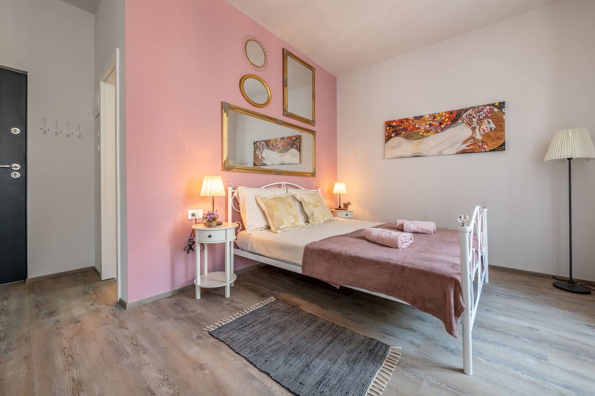A bedroom with a bed, bedside tables, a lamp, and a painting on the wall.