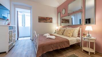 Un dormitorio con cama, mesitas de noche, cómoda y espejo.