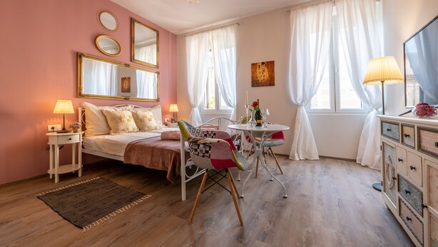 A bedroom with a bed, bedside tables, a chair, a small table, and a dresser. - Old City Studios 2 - Adults only (Pula)