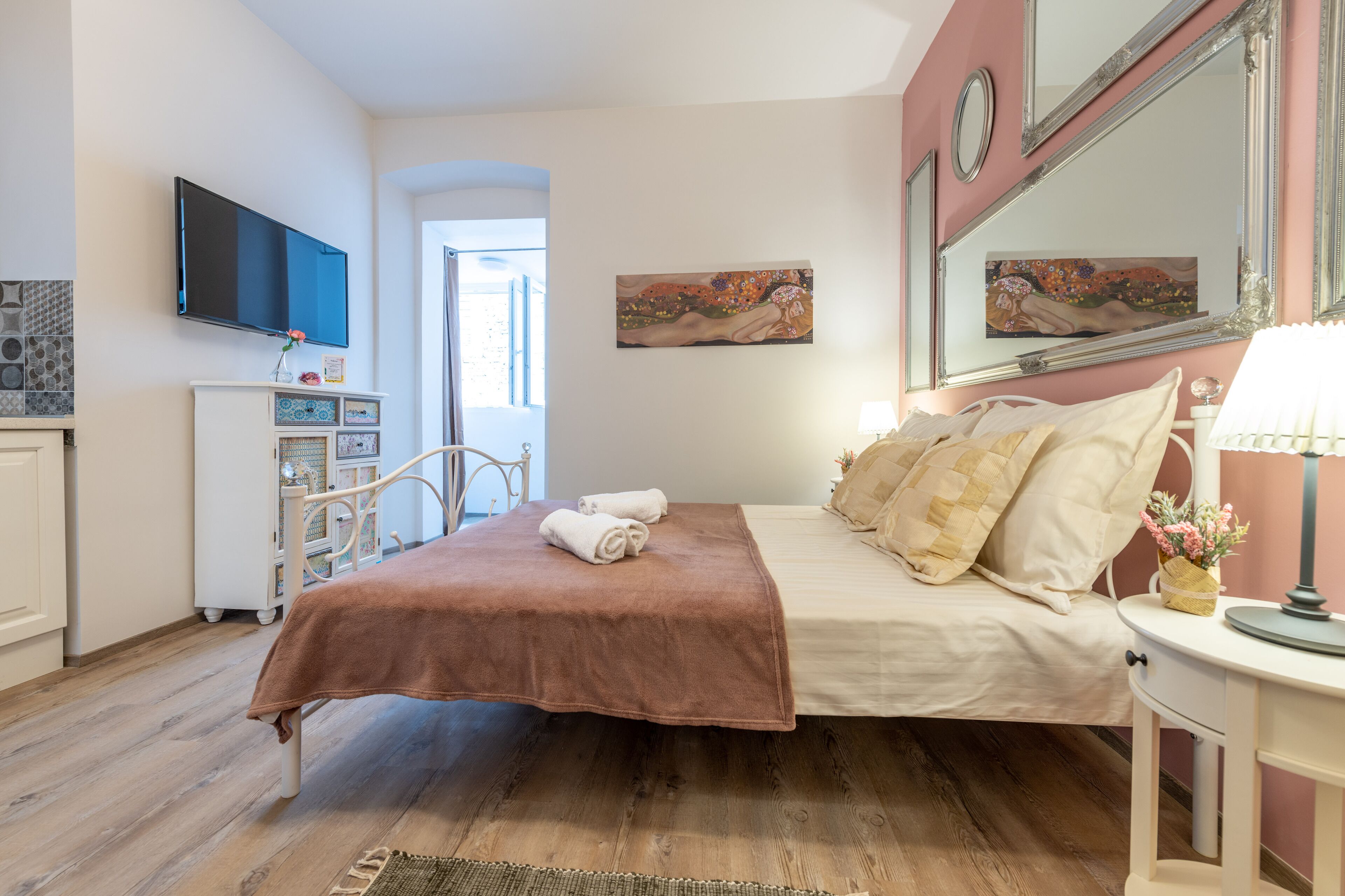 A bedroom with a bed, a TV, a dresser, and artwork on the walls.