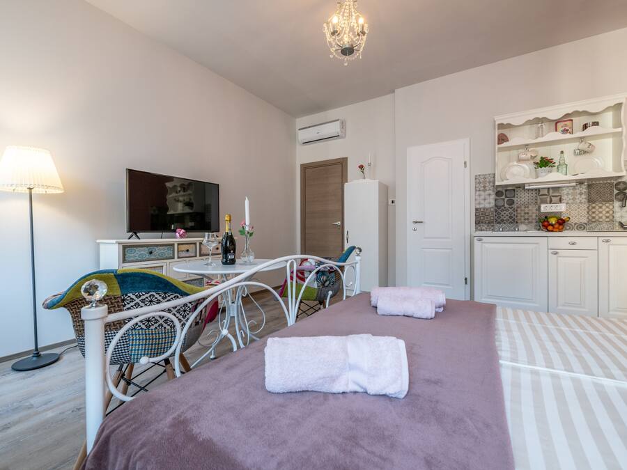 Un dormitorio con cama, mesita de noche, lámpara y vistas a la cocina.