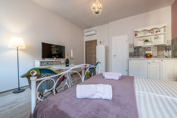 Un dormitorio con cama, mesita de noche, lámpara y vistas a la cocina.