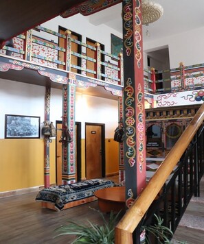 Ein traditionelles Interieur mit einer Holztreppe, aufwendigen Säulen und einem gemusterten Teppich.