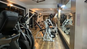 A gym with cardio machines, weightlifting equipment, and mirrors on the walls. - Hotel River Valley (Punakha)