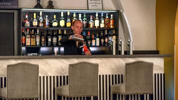 Un espace bar où un barman prépare une boisson. On peut voir des étagères remplies de différentes bouteilles derrière le bar.