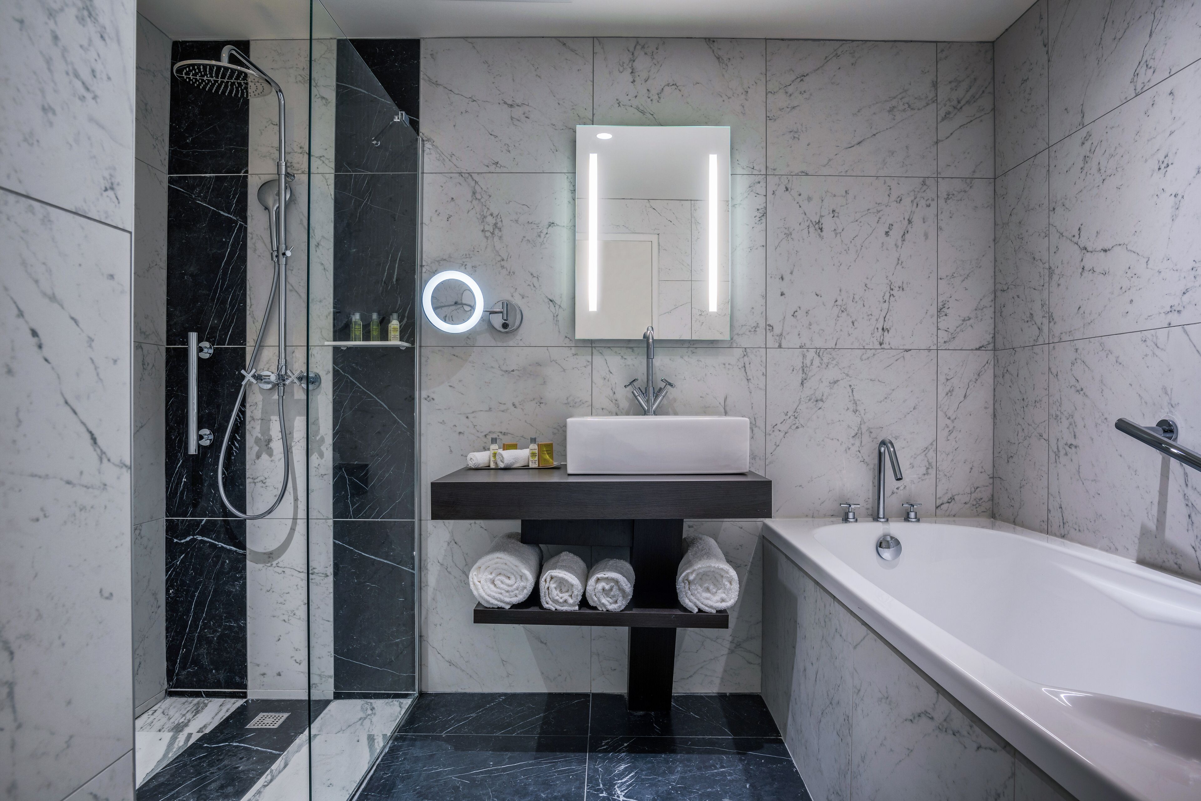 A modern bathroom with a glass-enclosed shower, a vanity with a mirror, and a bathtub.