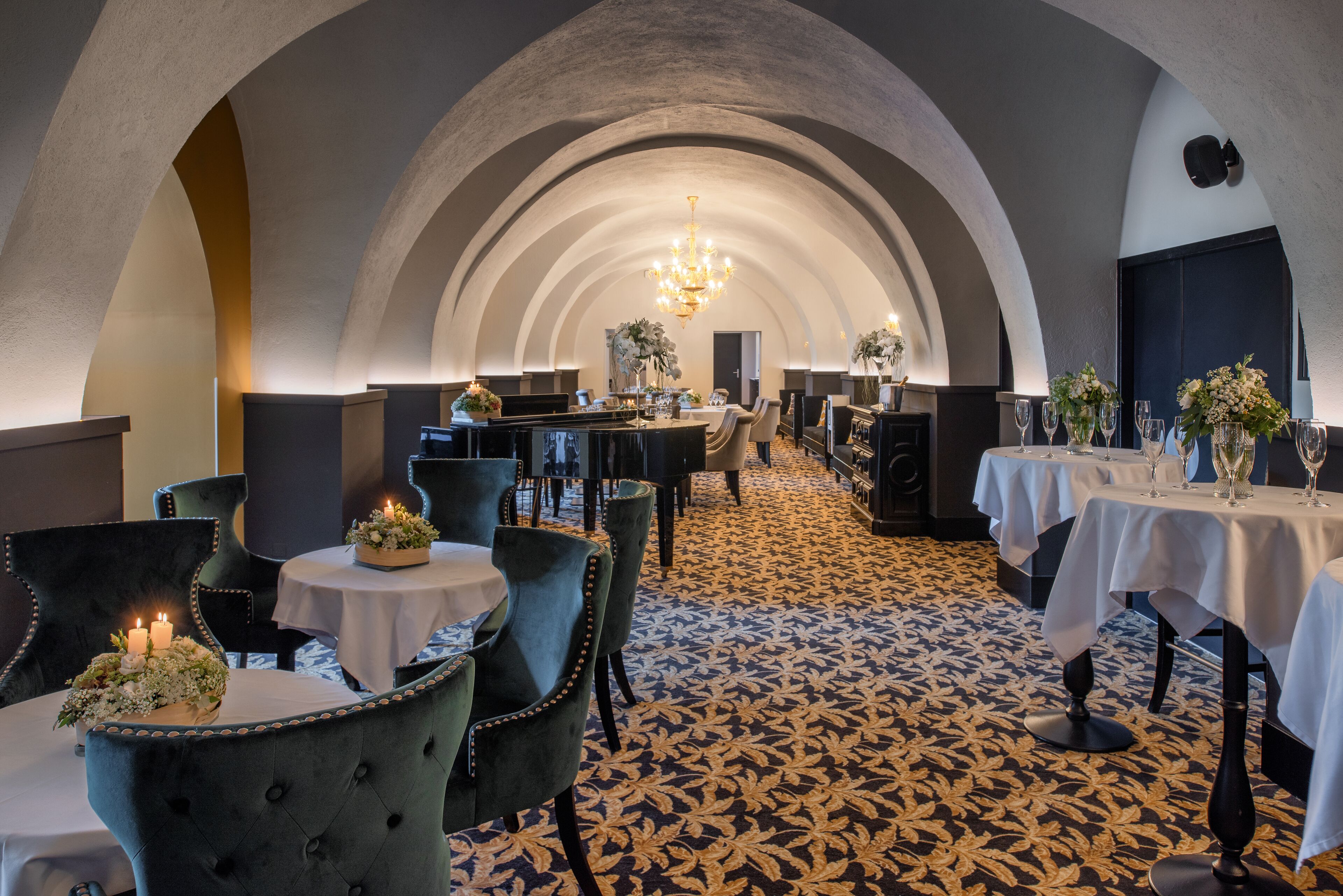 Un comedor de hotel con techos abovedados, mesas redondas y sillas.