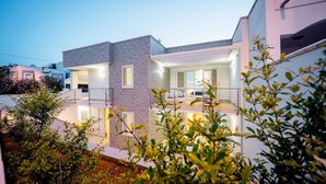 Una casa moderna de dos pisos con balcón, ventanas amplias y un interior bien iluminado.