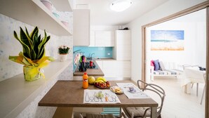 Una cocina moderna con armarios blancos, una encimera azul y un comedor con una mesa lista para dos personas.