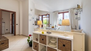 Una cocina moderna con una isla central, un comedor con mesa y sillas, y vistas al exterior a través de una ventana.