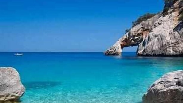Una playa costera despejada con formaciones rocosas y aguas turquesas tranquilas.