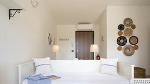 Un dormitorio ordenado con una cama, lámparas de noche, aire acondicionado instalado en la pared y un adorno decorativo en la pared.