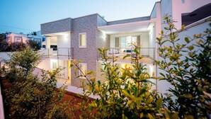 Ein modernes, zweistöckiges Haus mit Balkon, großen Fenstern und einem hellen Innenraum.