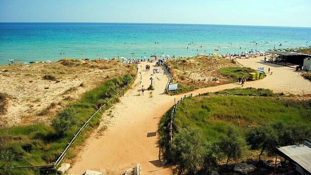 A beach with a sandy path leading to the water, surrounded by grassy areas and a few structures. - Arcangela Residence - Lentisk with Pool in Salento (Corsano)
