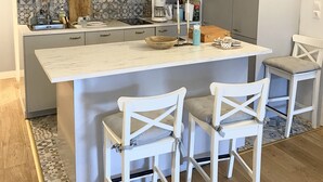 A modern kitchen with a central island, pendant lighting, and white cabinetry. - Small zen and cozy loft with well decorated terrace (Paris)