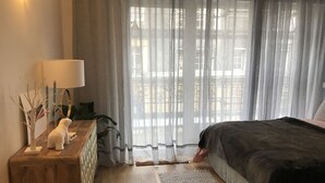 A bedroom with a bed, a bedside table with a lamp, a mirror, and a small white figurine. - Small zen and cozy loft with well decorated terrace (Paris)