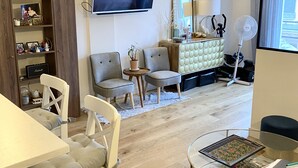 A modern living room with a flat-screen TV, a bookshelf, a dining area with chairs, a sofa, and a glass coffee table. - Small zen and cozy loft with well decorated terrace (Paris)