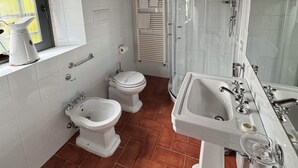 A compact bathroom with a toilet, bidet, and sink. There is a window with a view, and the floor is tiled. - Vinsantaia-Cozy barn on 2 levels (Reggello)