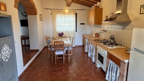 A kitchen with a wooden ceiling, tiled floor, and a dining area with a table and chairs. - Vinsantaia-Cozy barn on 2 levels (Reggello)