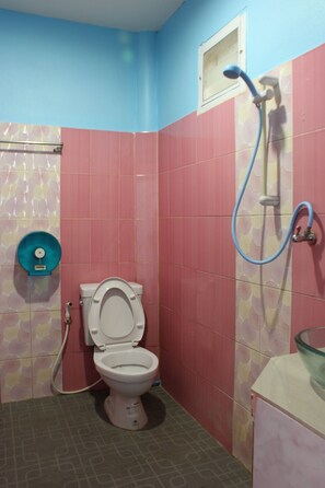 Un baño con paredes rosadas y azules, un inodoro, una ducha y un lavabo.