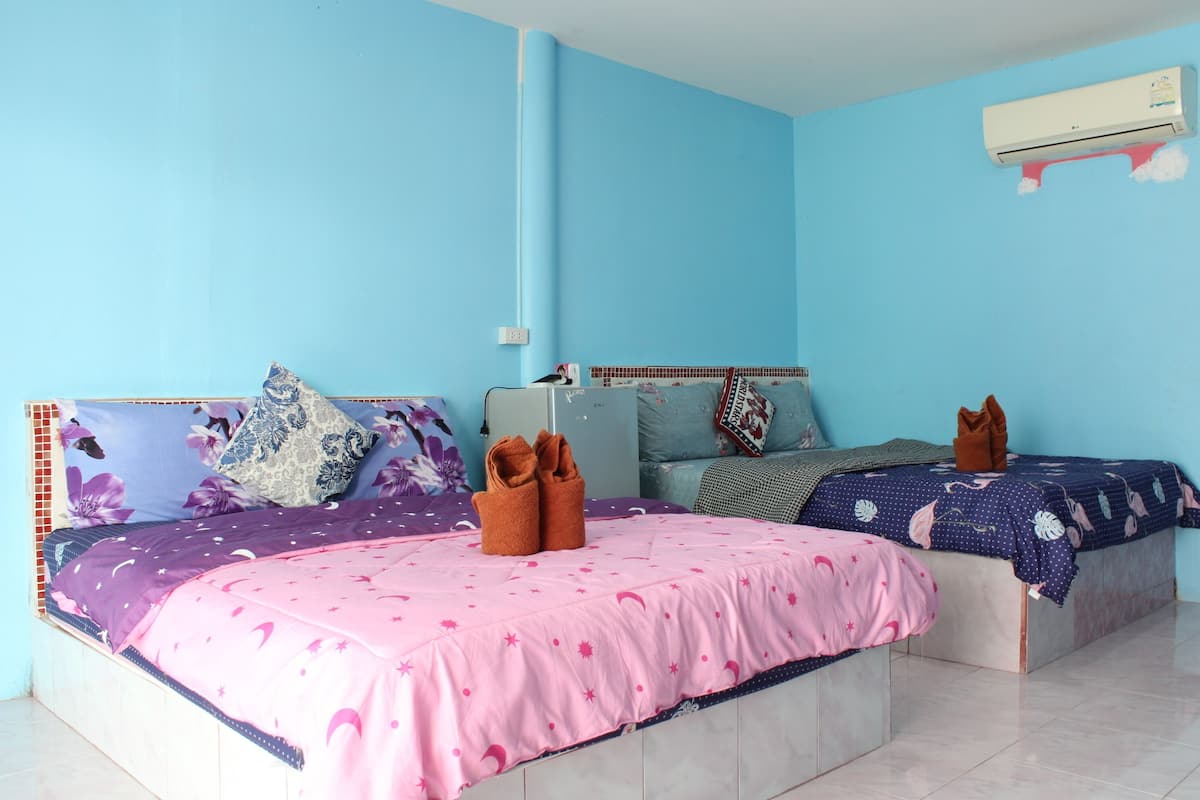 A room with two beds, each with a distinct floral-patterned headboard and pink bedding with star motifs.