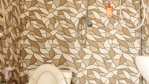 Un baño con pared estampada, inodoro y cabezal de ducha.