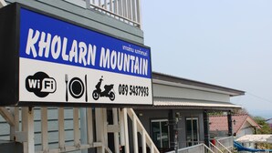 Señal para la Montaña Kholarn con Wi-Fi, restaurante y símbolo de motocicleta, además de un número de contacto.