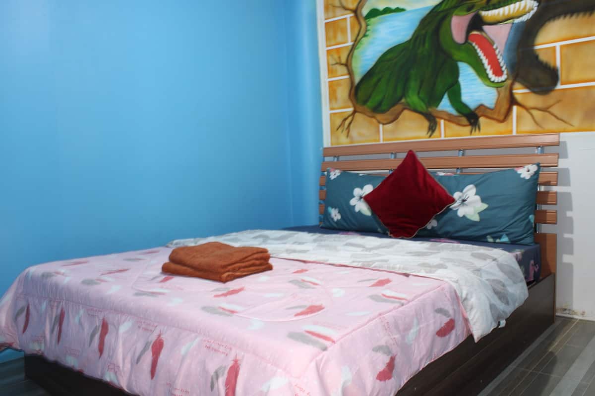 A bedroom with a bed, a pillow, a blanket, and a wall mural.