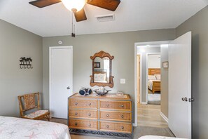 Een slaapkamer met een bed, een kaptafel, een stoel en een gang die naar een andere kamer leidt.