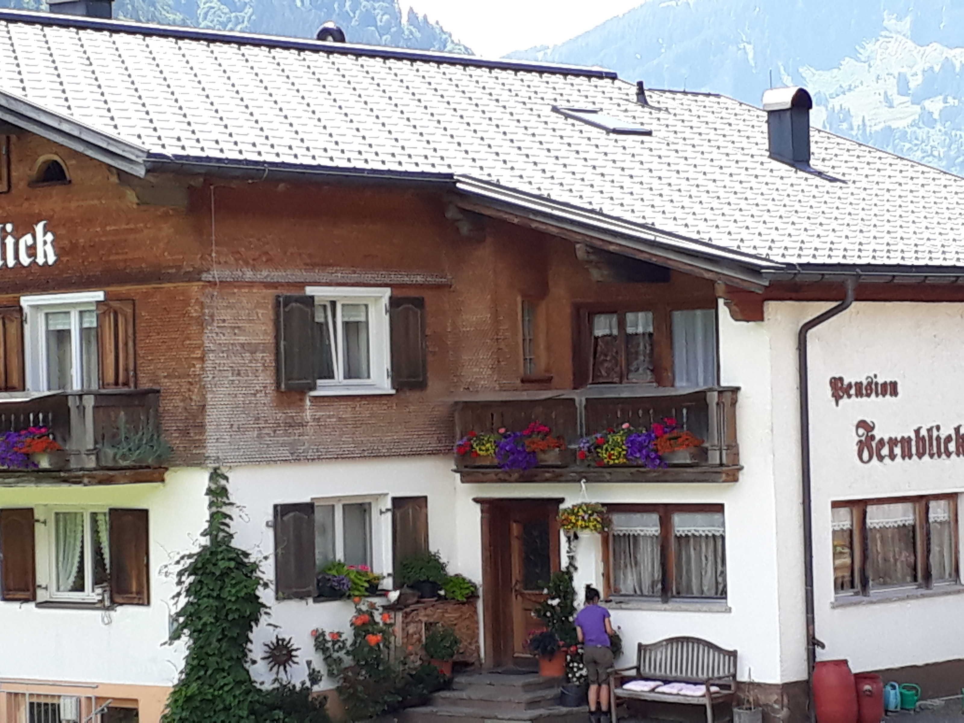 A traditional chalet with a balcony, flower boxes, and a wooden bench outside.