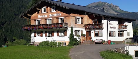 A traditional Alpine-style building with a sign 'Pension Fernblick' and a balcony with flower boxes.