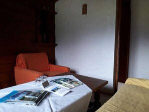 A room with a wooden chair, a small table with magazines, and a bed. - Double room (type A) Z-NR. 6 - Greber Christine - bed and breakfast Fernblick (Schoppernau)