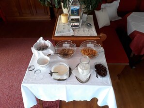 Taula de buffet de l'esmorzar amb diversos aliments, una espelma i una planta decorativa.