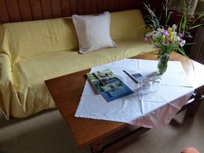 A wooden table with a white tablecloth, a vase with flowers, and some books and glasses on it. - Double room (type A) Z-NR. 6 - Greber Christine - bed and breakfast Fernblick (Schoppernau)