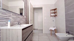 Een bad/douchecombinatie, een haardroger, een bidet, handdoeken